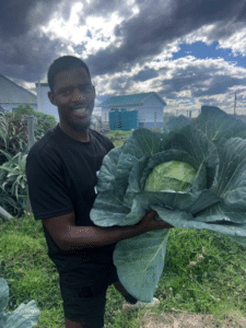 Pastor Thando holding a cabbage in his garden in Zithulele