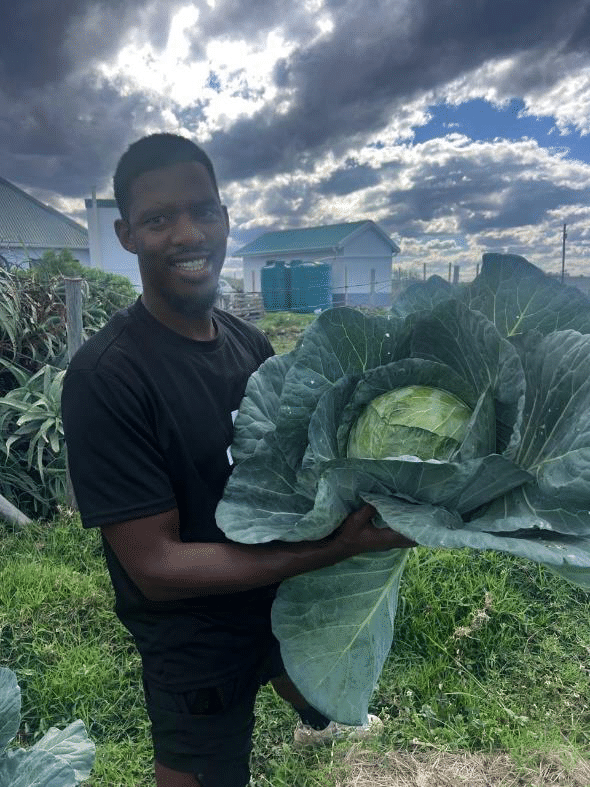 Pastor Thando holding a cabbage in his garden in Zithulele